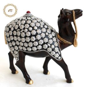 Handcrafted dark wood camel statue with silver floral metal embossing on a luxury marble table.